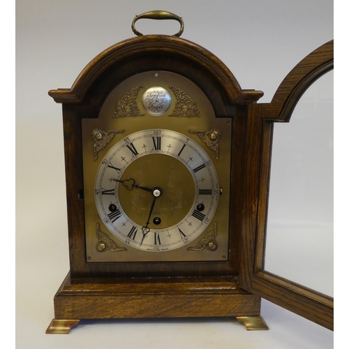 280 - A 20thC Elliot oak cased mantel clock, on a plinth and brass feet; the chiming movement faced by a b... 