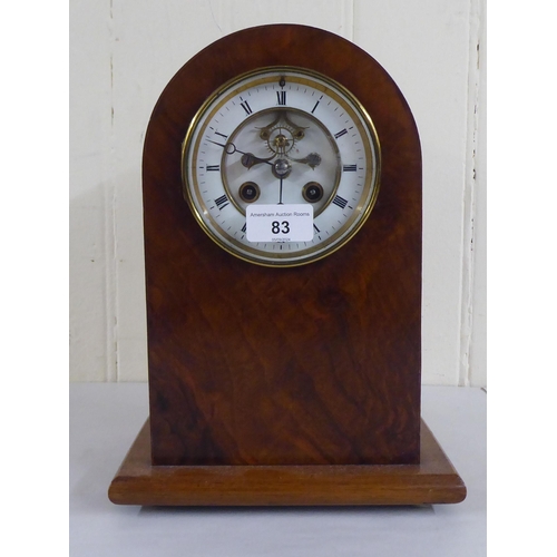 83 - An early 20thC mahogany and walnut finished, cased mantel clock; the 8 day movement faced by a skele... 