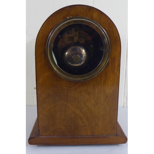 83 - An early 20thC mahogany and walnut finished, cased mantel clock; the 8 day movement faced by a skele... 