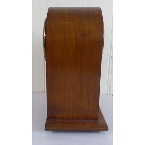 83 - An early 20thC mahogany and walnut finished, cased mantel clock; the 8 day movement faced by a skele... 