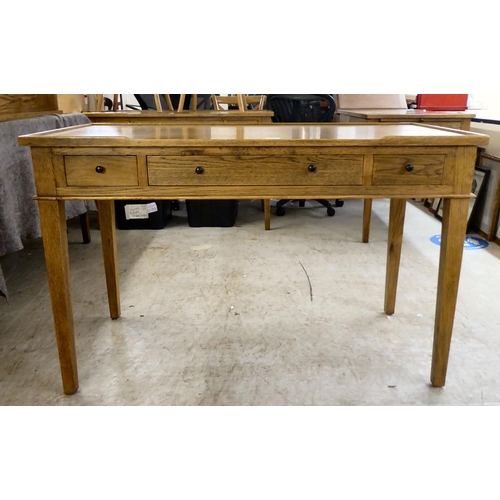 121 - A modern OKA oak desk with three drawers, raised on square, tapered legs  31