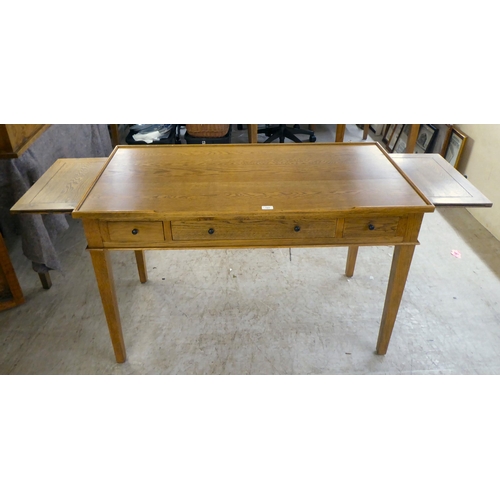 121 - A modern OKA oak desk with three drawers, raised on square, tapered legs  31