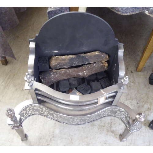 123 - A cast iron and steel fireplace with turned finials, raised on square, tapered feet  27