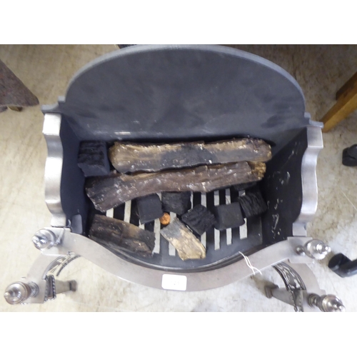 123 - A cast iron and steel fireplace with turned finials, raised on square, tapered feet  27