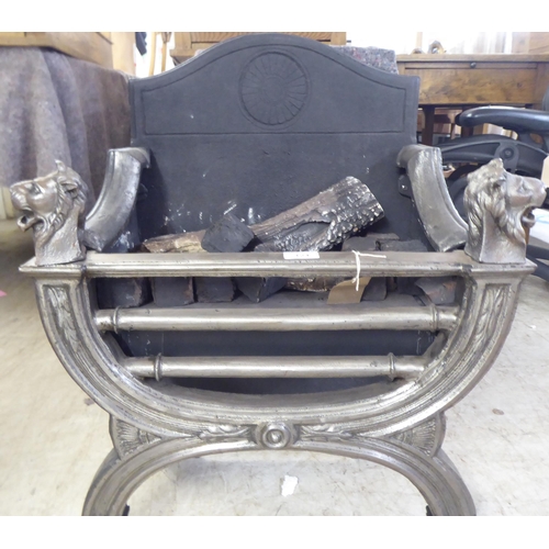 124 - A cast iron and steel fireplace with lion mask finials, raised on paw feet  28