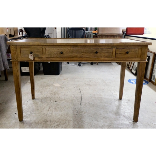 125 - A modern OKA oak desk with three drawers, raised on square, tapered legs  31