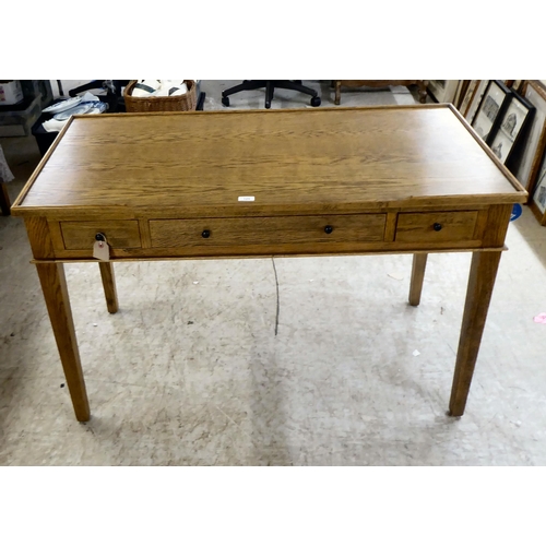 125 - A modern OKA oak desk with three drawers, raised on square, tapered legs  31