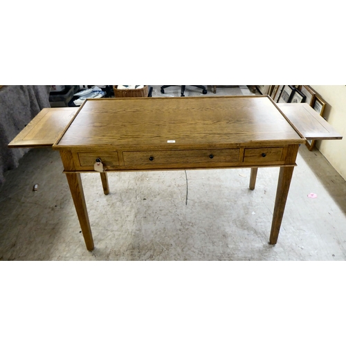 125 - A modern OKA oak desk with three drawers, raised on square, tapered legs  31