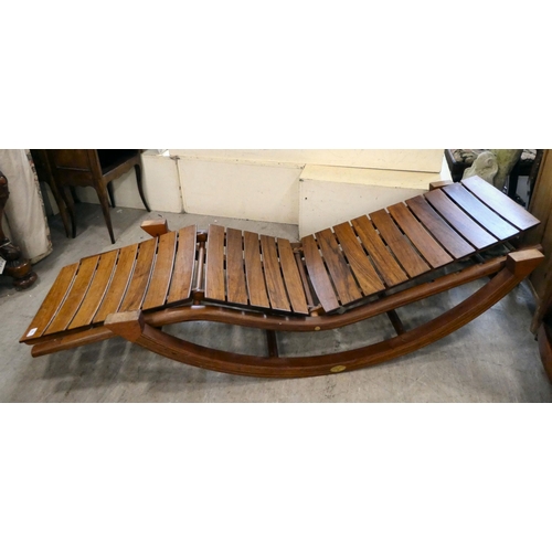 135 - A David Craig teak garden lounger of slatted construction, on an arched base 