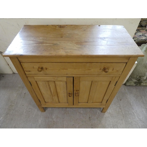 140 - A mid 20thC pine cabinet with two drawers and two doors, raised on block legs  31