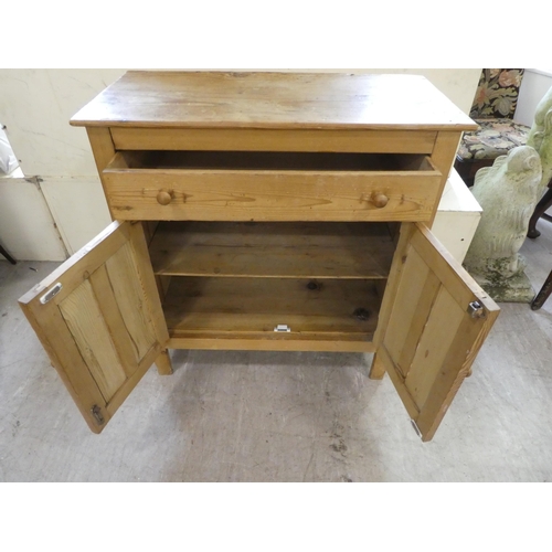 140 - A mid 20thC pine cabinet with two drawers and two doors, raised on block legs  31