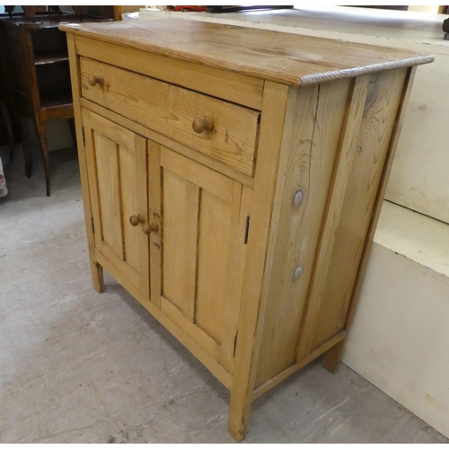 140 - A mid 20thC pine cabinet with two drawers and two doors, raised on block legs  31