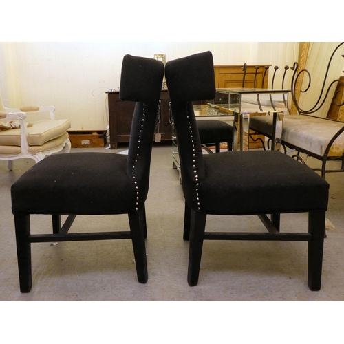 153 - A pair of modern curved back chairs, upholstered in black fabric, decorated with studs