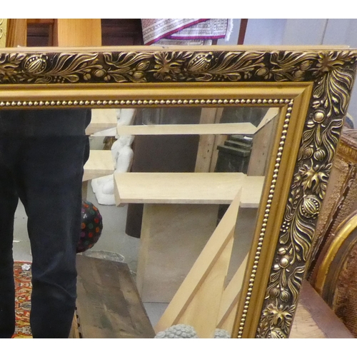 210 - A modern mirror, the bevelled plate set in a gilt frame with floral decoration  44