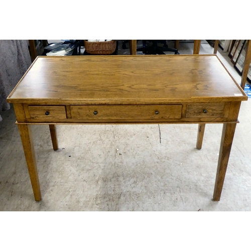 278 - A modern OKA oak desk with three drawers, raised on square, tapered legs  31