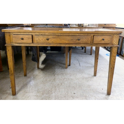 32 - A modern OKA oak desk with three drawers, raised on square, tapered legs  31