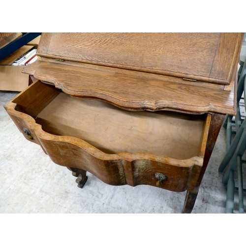 36 - A 1930s limed oak bureau with a fall flap and two drawers, raised on curved legs  37