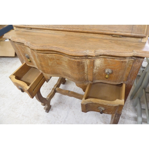 36 - A 1930s limed oak bureau with a fall flap and two drawers, raised on curved legs  37