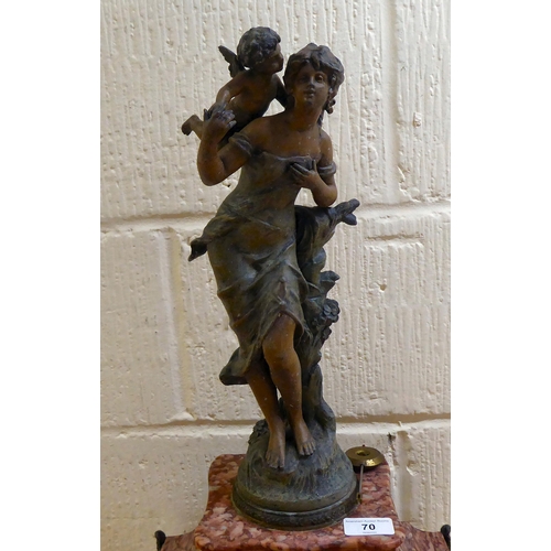 70 - A late Victorian mottled red marble mantel clock, surmounted by a spelter female figure; the 8 day m... 