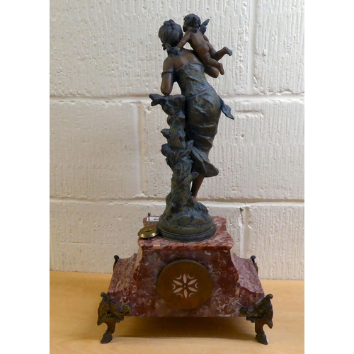 70 - A late Victorian mottled red marble mantel clock, surmounted by a spelter female figure; the 8 day m... 