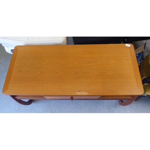 57 - A mid century Parker Knoll teak coffee table with a drawer and two open sections, raised on curved l... 