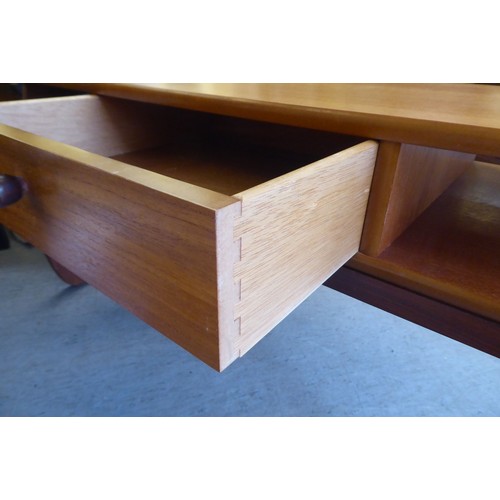 57 - A mid century Parker Knoll teak coffee table with a drawer and two open sections, raised on curved l... 