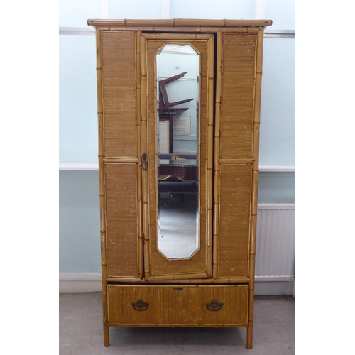 231 - A post World War II Oriental style bamboo and rattan finished wardrobe with a central mirrored door,... 