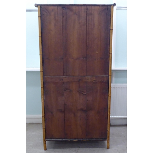 231 - A post World War II Oriental style bamboo and rattan finished wardrobe with a central mirrored door,... 