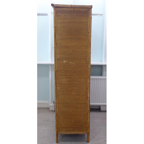 231 - A post World War II Oriental style bamboo and rattan finished wardrobe with a central mirrored door,... 