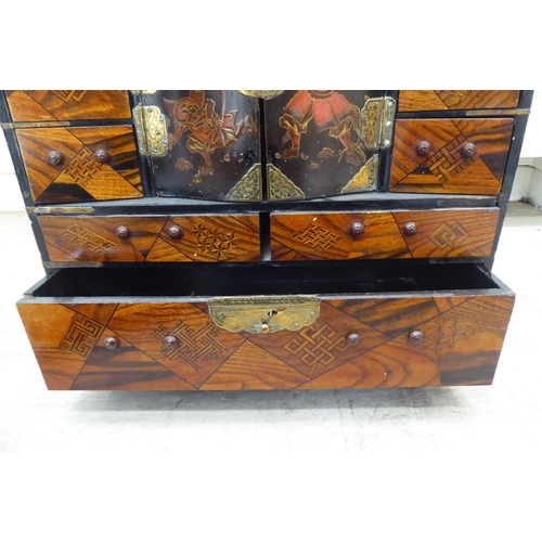 237 - A 20thC Japanese black painted and fruitwood marquetry inlaid table top cabinet with an arrangement ... 