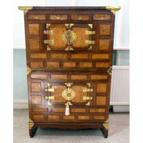 241 - A 20thC Korean brass bound fruitwood chest with an arrangement of cupboard doors and drawers, in two... 