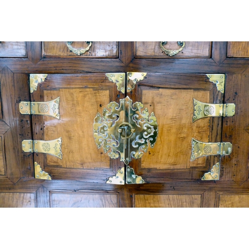 241 - A 20thC Korean brass bound fruitwood chest with an arrangement of cupboard doors and drawers, in two... 