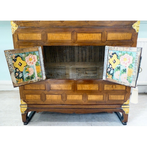 241 - A 20thC Korean brass bound fruitwood chest with an arrangement of cupboard doors and drawers, in two... 