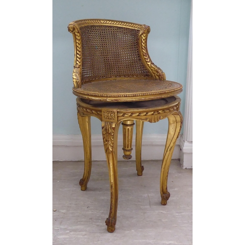 302 - A late 19thC French giltwood, revolving dressing table chair with a caned back and seat, raised on c... 