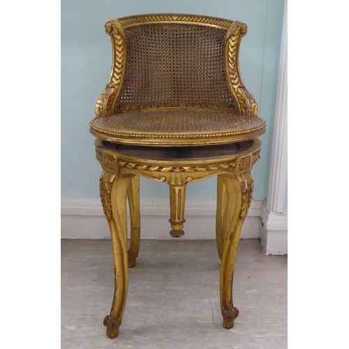 302 - A late 19thC French giltwood, revolving dressing table chair with a caned back and seat, raised on c... 