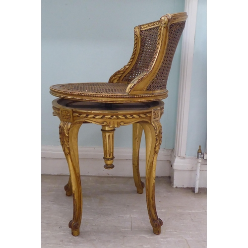 302 - A late 19thC French giltwood, revolving dressing table chair with a caned back and seat, raised on c... 