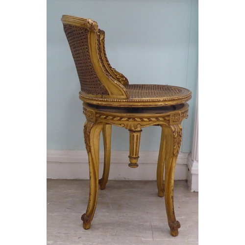 302 - A late 19thC French giltwood, revolving dressing table chair with a caned back and seat, raised on c... 