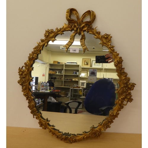 140 - A mid 20thC mirror, the oval plate set in a cast gilt metal ribbon and foliage frame  27