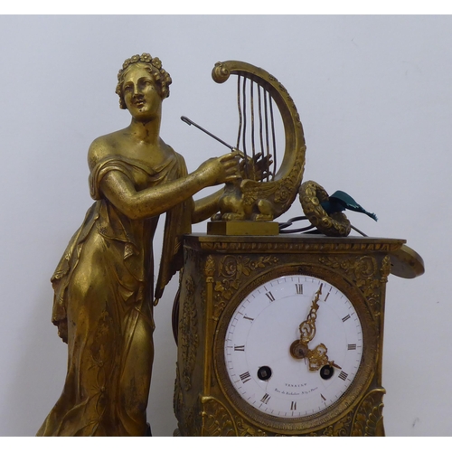 150 - An early 20thC French gilt metal cased mantel clock with a figure and harp; the Venault of Paris mov... 