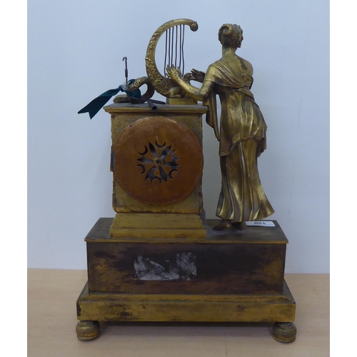 150 - An early 20thC French gilt metal cased mantel clock with a figure and harp; the Venault of Paris mov... 