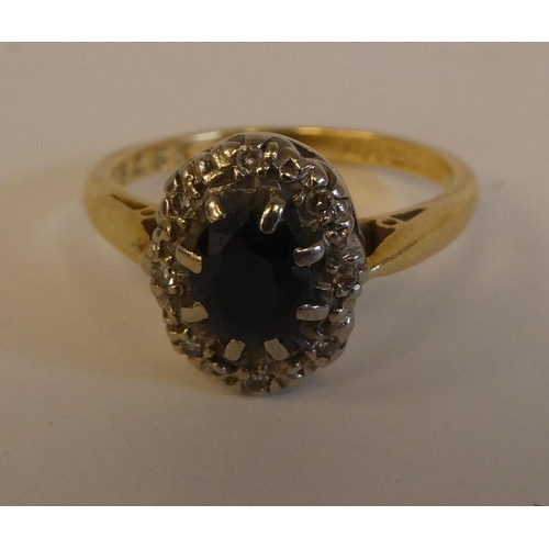 290 - An 18ct gold ring, set with a dark blue stone, surrounded by white stones