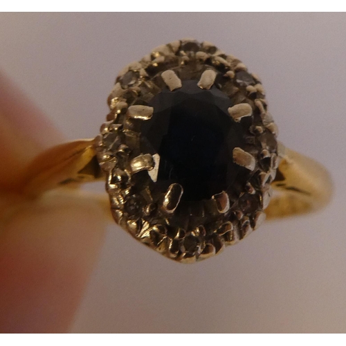 290 - An 18ct gold ring, set with a dark blue stone, surrounded by white stones