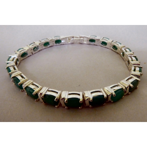 338 - A silver coloured metal bracelet, claw set with emeralds and cubic zirconia