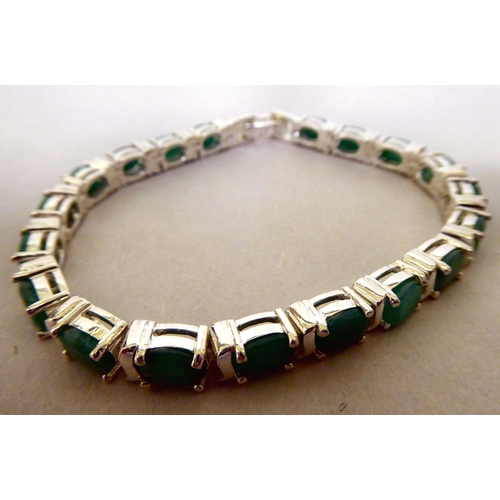 338 - A silver coloured metal bracelet, claw set with emeralds and cubic zirconia