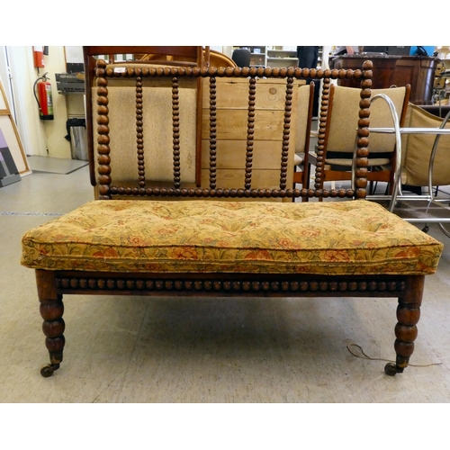 397 - A late Victorian faux rosewood framed bobbin turned salon settee, raised on casters 