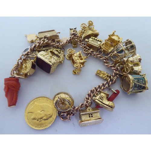 405 - A 9ct gold charm bracelet with various charms, featuring an apple containing Adam & Eve, a parro... 