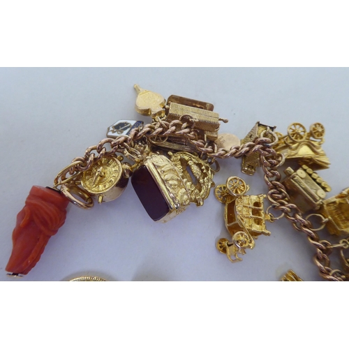 405 - A 9ct gold charm bracelet with various charms, featuring an apple containing Adam & Eve, a parro... 