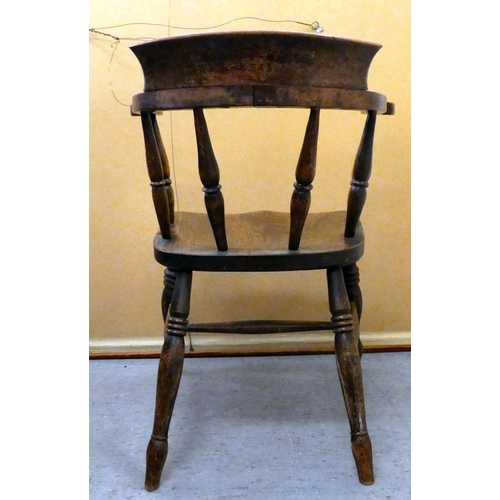 409 - An early 20thC elm and beech framed captain's chair with a solid seat, raised on turned legs