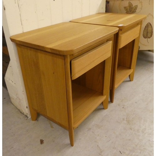 74 - A pair of modern light oak bedside chests with a single drawer, over an open shelf, raised on straig... 