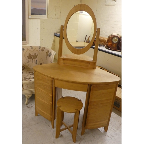 77 - A modern light oak dressing table, surmounted by an oval mirror and single drawer base, over two ped... 